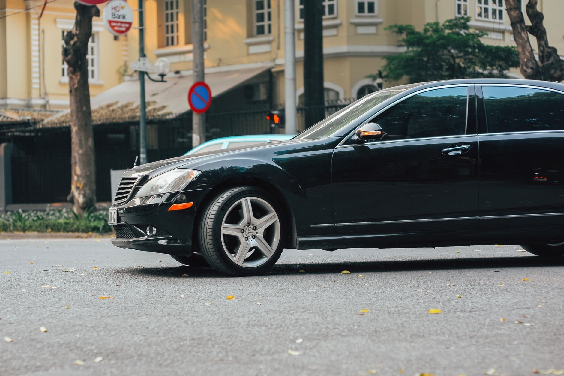 A black luxury sedan parked on an urban street near a bank building, showcasing elegance and style.